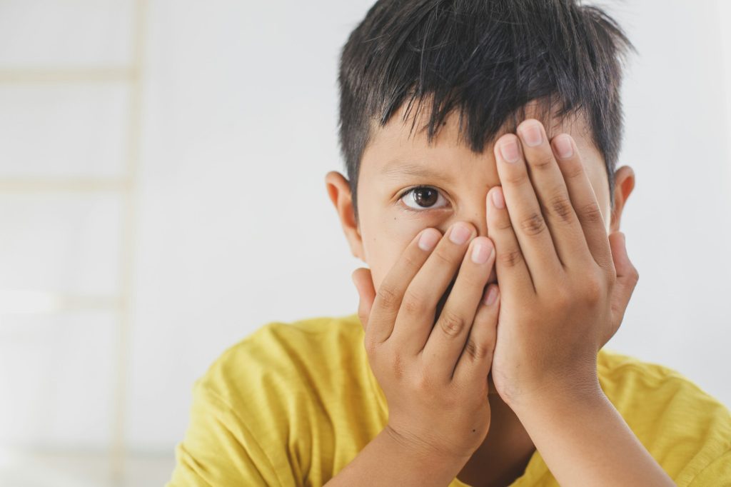 Child peep closing his one eye with hand