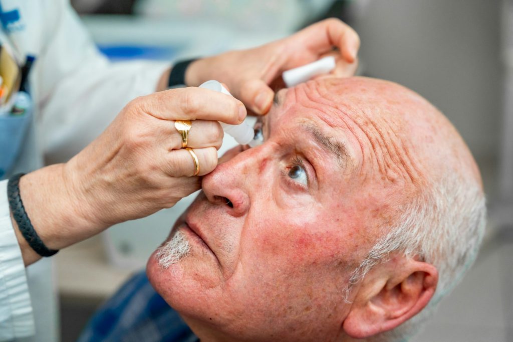 Ophthalmologist pouring drops to dilate the pupil to a man