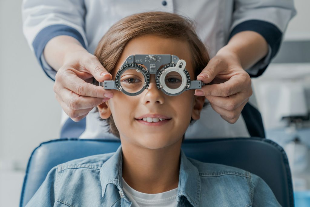 Smiling child boy in glasses checks eye vision at pediatric ophthalmologist